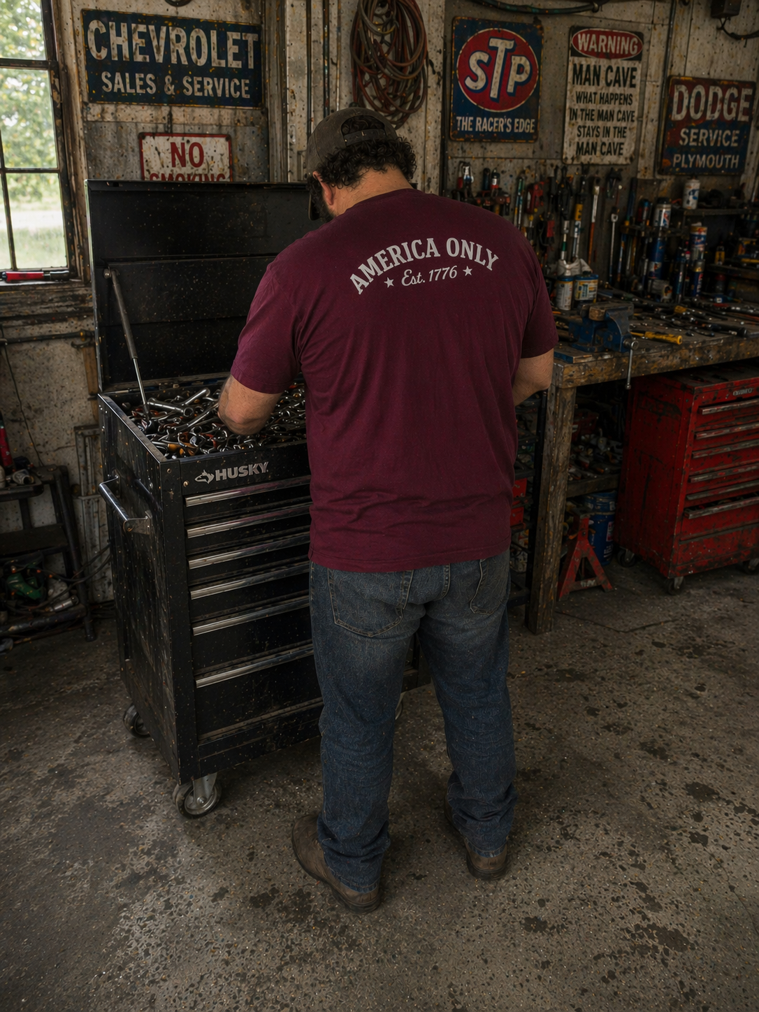 Person wearing a maroon t-shirt with 'America Only' text in a garage setting.