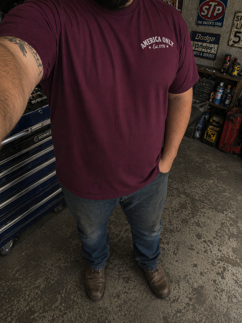 Person wearing a maroon t-shirt with 'America Only' text in a garage setting.